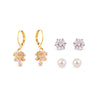 Set of gold earrings with floral designs, silver stud earrings, and pearl earrings on a white background