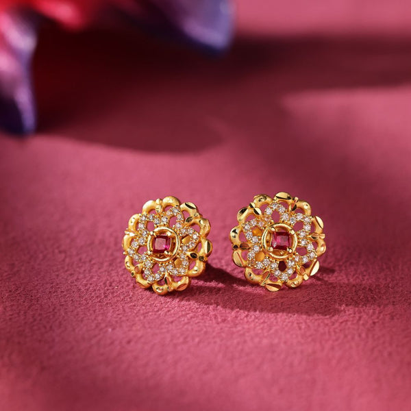 Gold earrings with gemstones on a pink fabric background