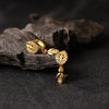 Gold earrings with leaf design on a dark surface