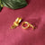 Gold earrings on a textured red surface