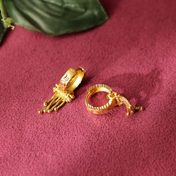 Gold earrings on a textured red surface
