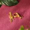Gold hoop earrings with intricate designs on a pink textured surface