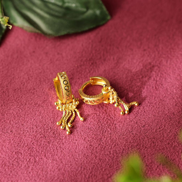 Gold hoop earrings with intricate designs on a pink textured surface