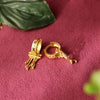 Gold hoop earrings with intricate designs on a red fabric background
