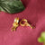 Gold hoop earrings with intricate designs on a red fabric background