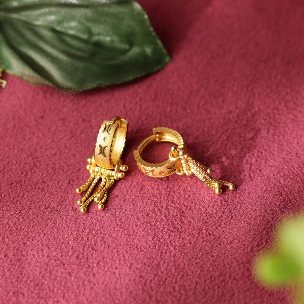 Gold hoop earrings with intricate designs on a red fabric background