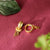 Gold hoop earrings on a textured red surface with green leaves.