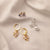 Set of gold and pearl earrings on a beige fabric background